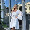 Woman wearing white long sleeve ruffle dress - bohemian beach wedding guest outfit